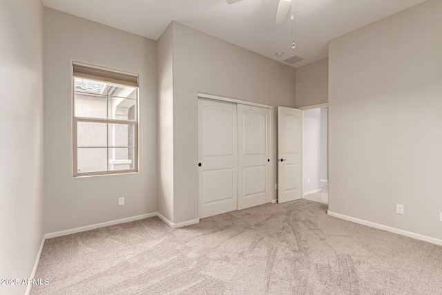 unfurnished bedroom with a closet, light colored carpet, and ceiling fan