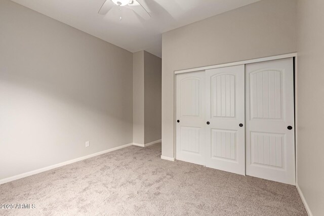 unfurnished bedroom featuring ceiling fan, a closet, and light colored carpet