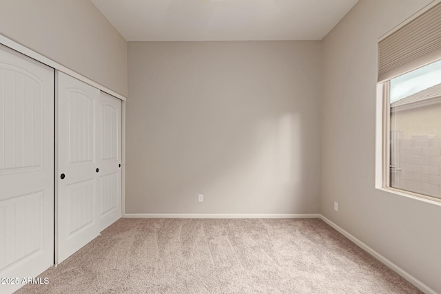 unfurnished bedroom featuring light colored carpet and a closet