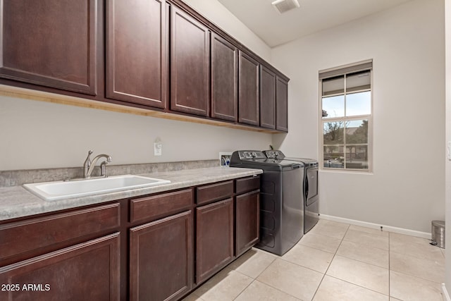 laundry room featuring washing machine and clothes dryer, sink, light tile patterned floors, and cabinets