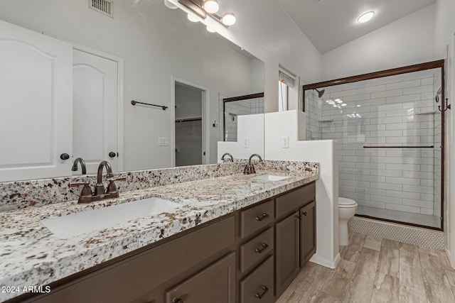 bathroom featuring walk in shower, wood-type flooring, lofted ceiling, toilet, and vanity