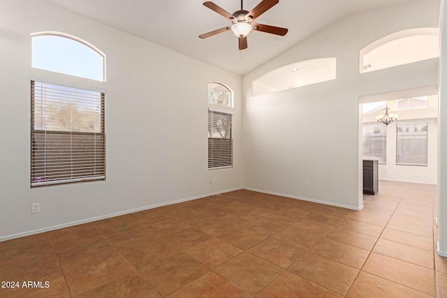 empty room with tile patterned floors, ceiling fan with notable chandelier, and high vaulted ceiling