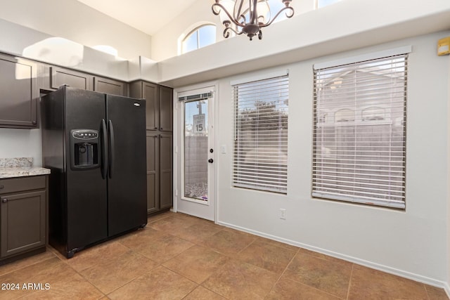 kitchen featuring dark brown cabinets, lofted ceiling, black refrigerator with ice dispenser, and an inviting chandelier