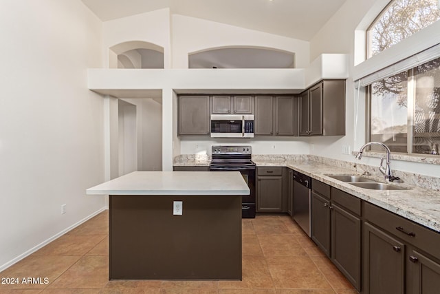 kitchen featuring a center island, high vaulted ceiling, sink, light tile patterned flooring, and stainless steel appliances