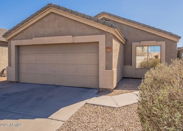 single story home featuring a garage, driveway, a tile roof, and stucco siding