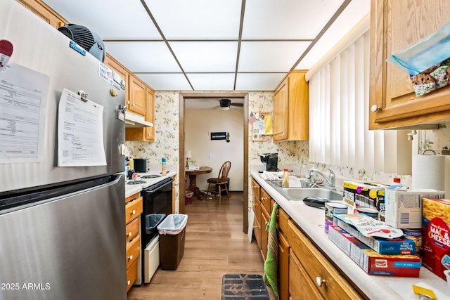 kitchen featuring light countertops, electric range, freestanding refrigerator, and a sink