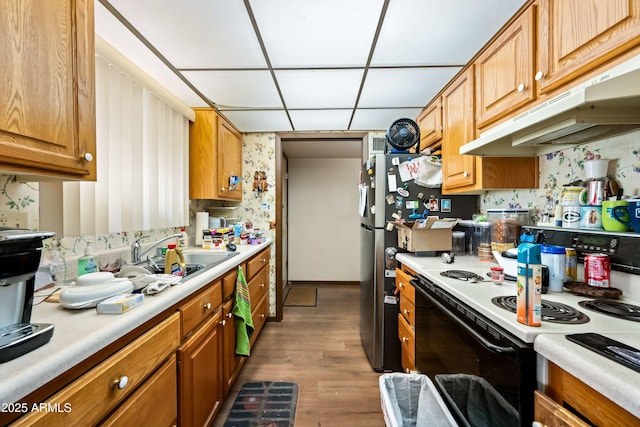 kitchen featuring under cabinet range hood, light countertops, freestanding refrigerator, and electric stove