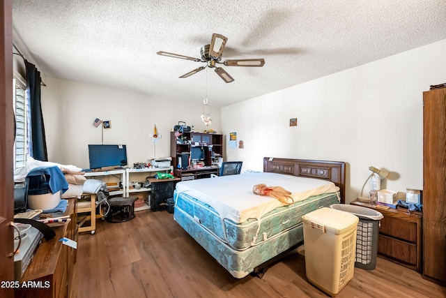 bedroom featuring a ceiling fan, wood finished floors, and a textured ceiling