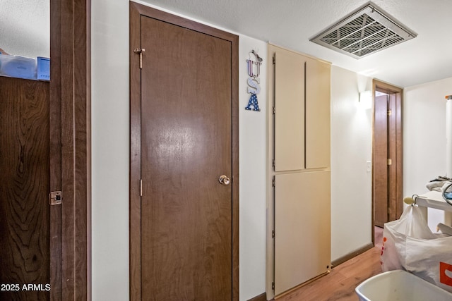 hallway with light wood-style floors and visible vents