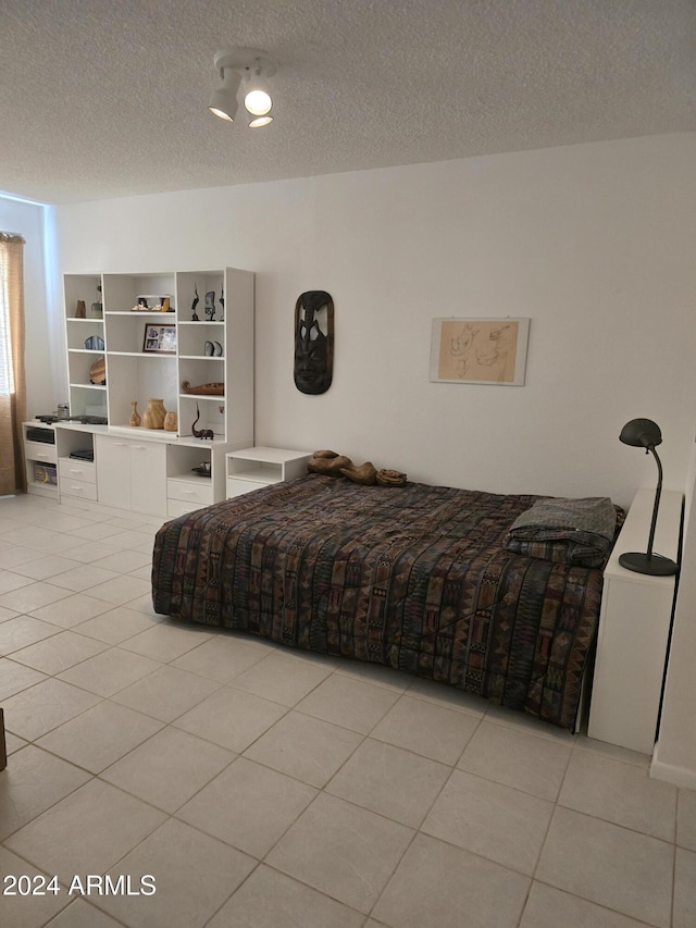 bedroom with light tile patterned flooring and a textured ceiling