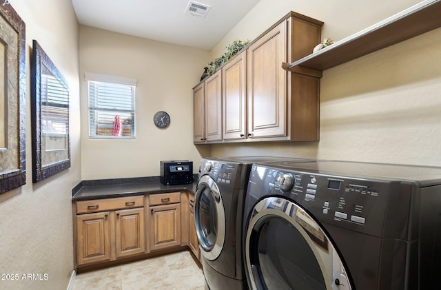 clothes washing area with cabinets and washing machine and clothes dryer