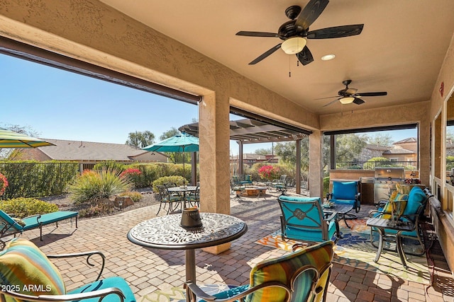 view of patio with exterior kitchen, a fire pit, and ceiling fan