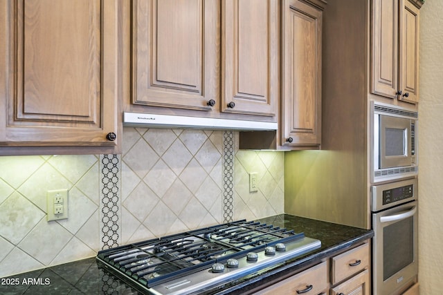 kitchen with decorative backsplash, dark stone countertops, and appliances with stainless steel finishes