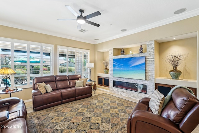 living room featuring ornamental molding, ceiling fan, a stone fireplace, and built in shelves