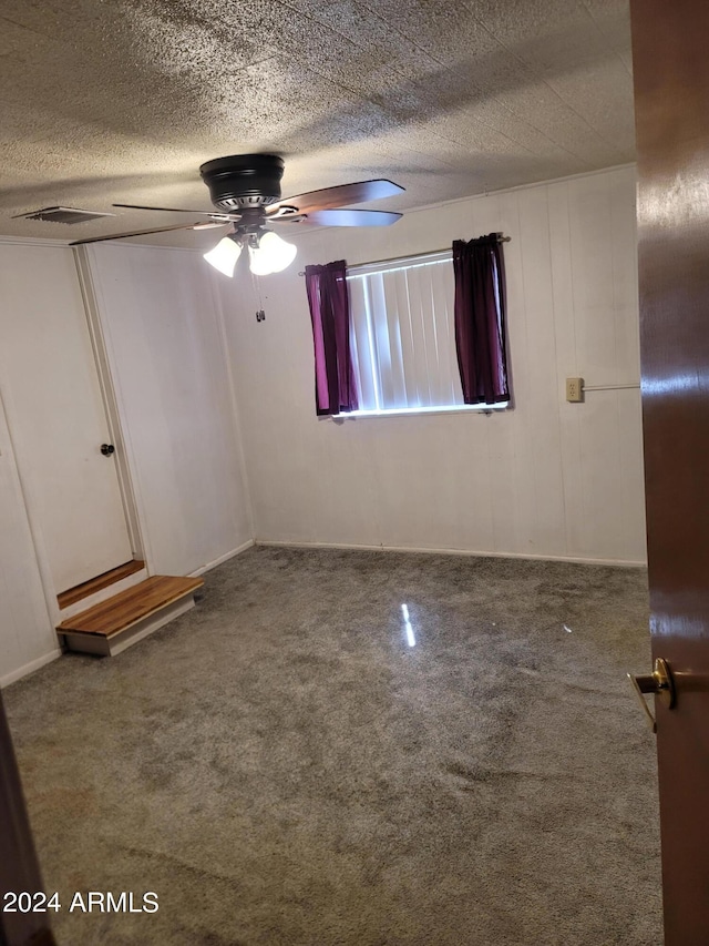 spare room with carpet flooring, ceiling fan, and a textured ceiling