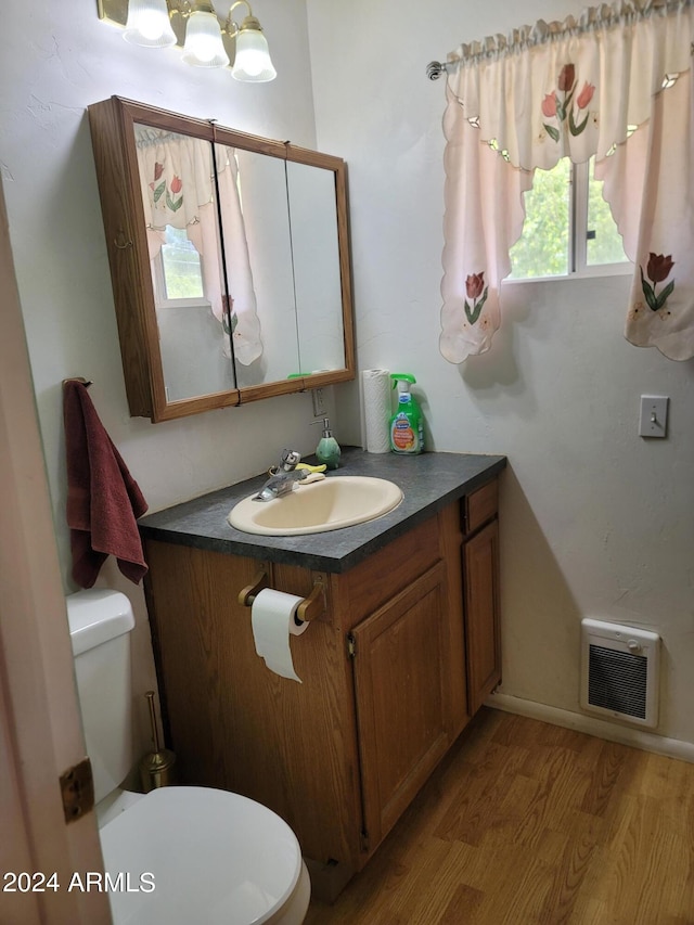 bathroom featuring a notable chandelier, vanity, toilet, and wood-type flooring