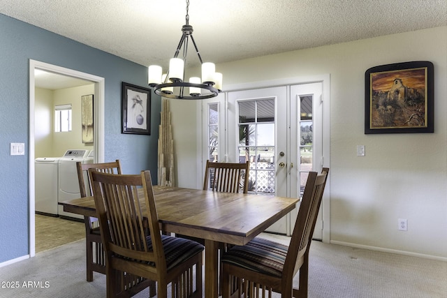 dining area with a textured ceiling, light carpet, a notable chandelier, and washer and clothes dryer