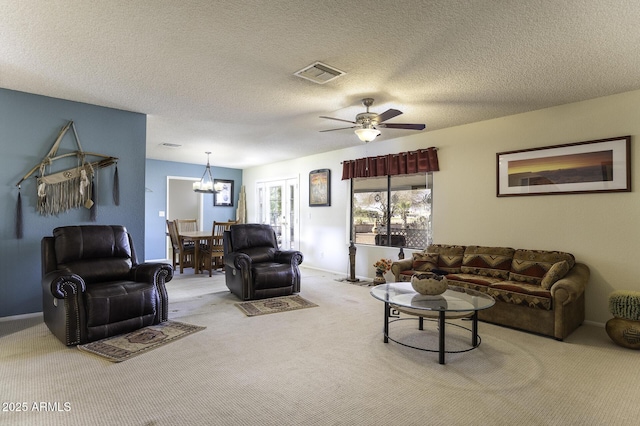 carpeted living room featuring baseboards, ceiling fan with notable chandelier, visible vents, and a textured ceiling