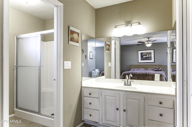 ensuite bathroom featuring vanity, a stall shower, ceiling fan, a textured wall, and connected bathroom