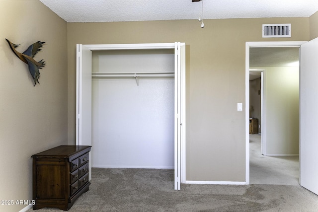 unfurnished bedroom featuring visible vents, baseboards, carpet, a closet, and a textured ceiling