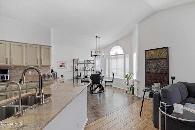 living area with vaulted ceiling, a notable chandelier, and light wood-type flooring
