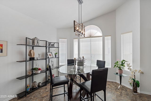 dining space with baseboards, stone finish flooring, and a notable chandelier