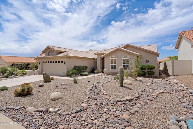 view of front facade with a gate, concrete driveway, a tiled roof, an attached garage, and stucco siding