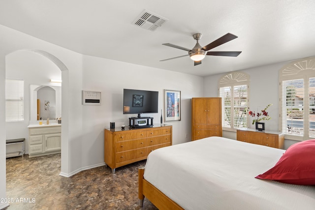 bedroom with visible vents, a ceiling fan, arched walkways, baseboards, and ensuite bathroom