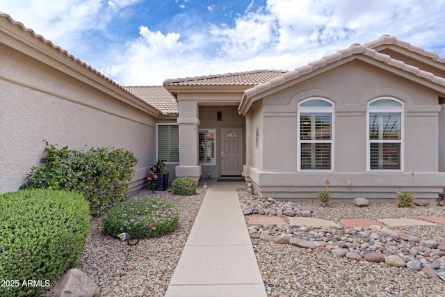 entrance to property featuring a tile roof and stucco siding