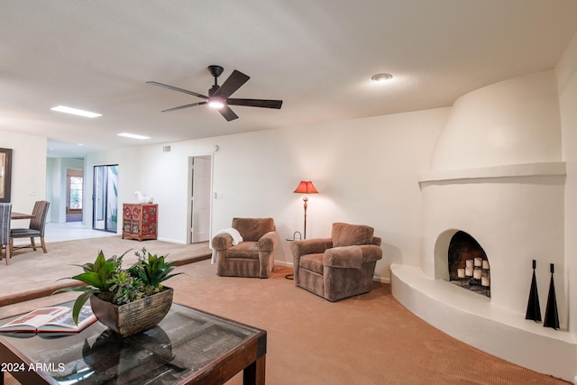 carpeted living room with a large fireplace and ceiling fan