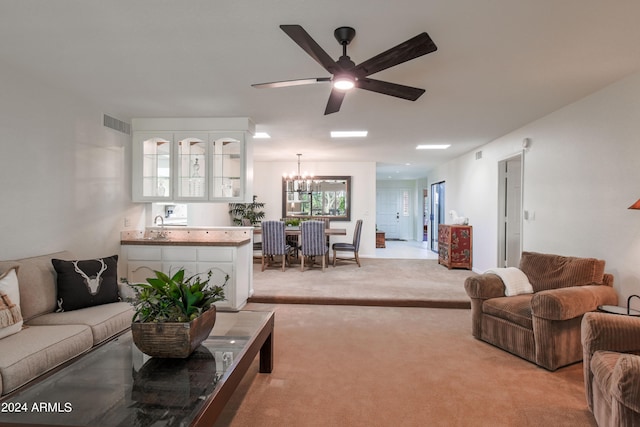 carpeted living room featuring ceiling fan with notable chandelier