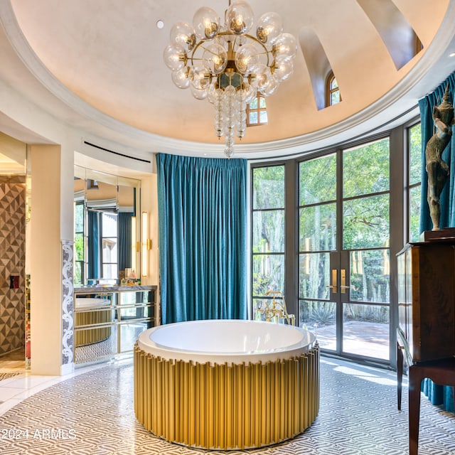 full bath with a notable chandelier, ornamental molding, french doors, tile patterned flooring, and a soaking tub