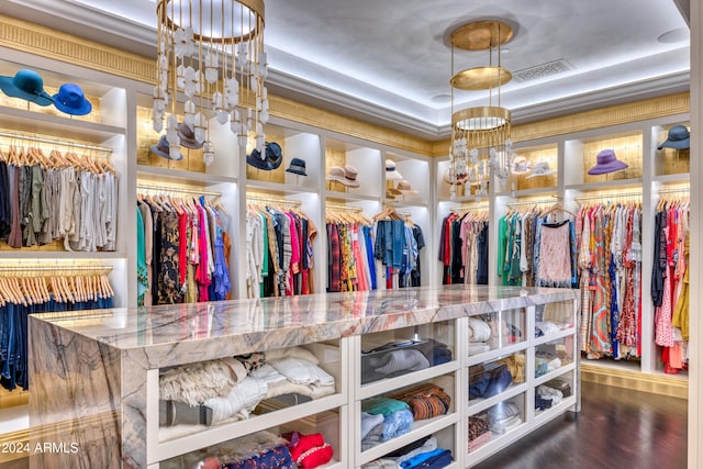 spacious closet with a tray ceiling, a notable chandelier, wood finished floors, and visible vents