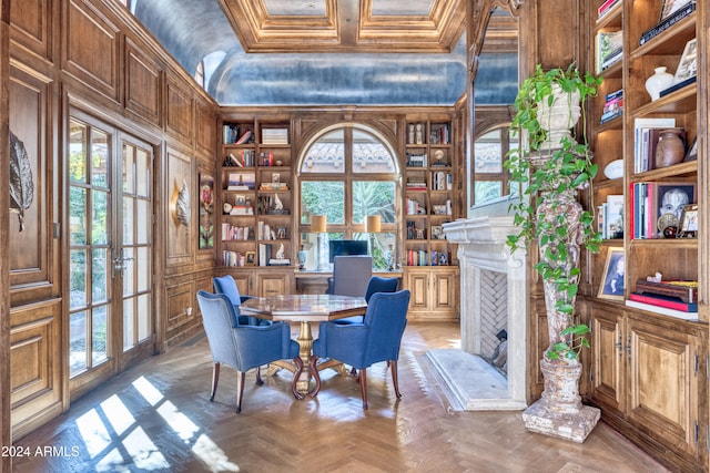 office area with built in shelves, coffered ceiling, a fireplace with raised hearth, ornamental molding, and wood walls