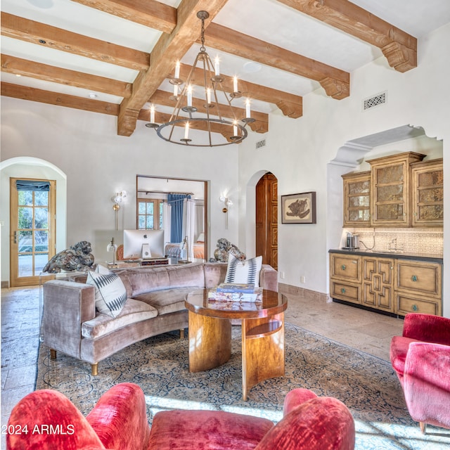 living area featuring visible vents, baseboards, beamed ceiling, arched walkways, and a notable chandelier