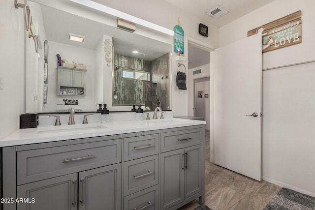 bathroom featuring double vanity, a stall shower, visible vents, and a sink