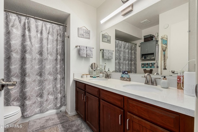 full bathroom with a sink, visible vents, toilet, and double vanity