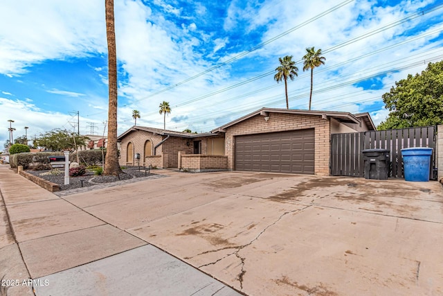 view of front facade with concrete driveway, fence, brick siding, and a garage