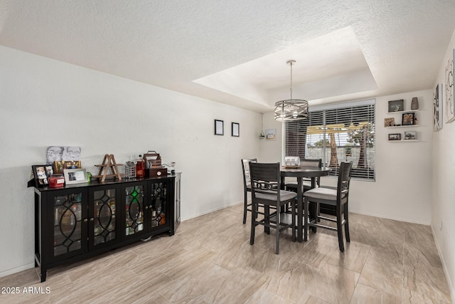 dining space featuring a raised ceiling, baseboards, and a textured ceiling