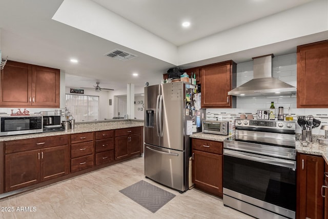 kitchen with visible vents, ceiling fan, light stone countertops, stainless steel appliances, and wall chimney exhaust hood