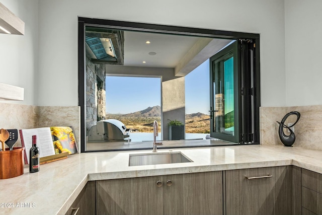 kitchen with a mountain view, dark brown cabinetry, and sink