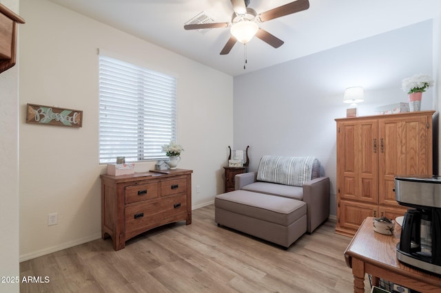 living area with light wood finished floors, a ceiling fan, and baseboards