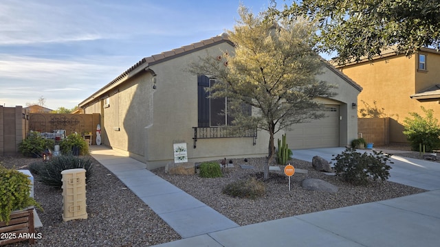 view of front facade featuring fence, concrete driveway, and stucco siding