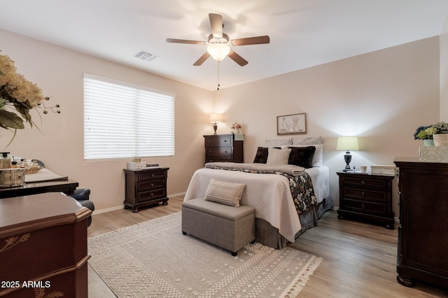 bedroom featuring baseboards, visible vents, ceiling fan, and light wood finished floors