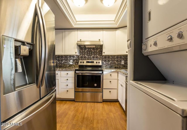 11026 N 28th Dr Unit 34, Phoenix, AZ 85029 - kitchen with stainless steel appliances, estacked washer and dryer, under cabinet range hood, a raised ceiling, and tasteful backsplash