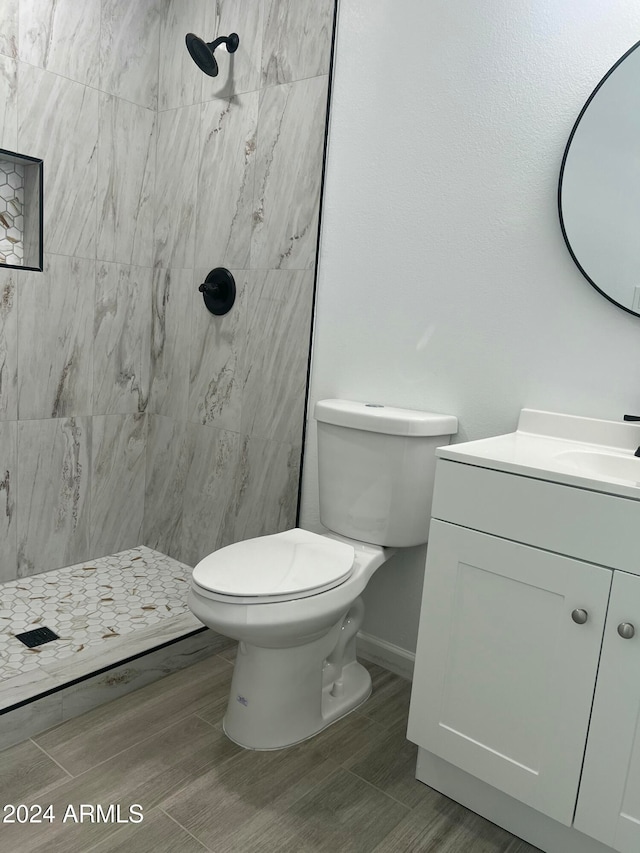 bathroom with vanity, a tile shower, hardwood / wood-style flooring, and toilet