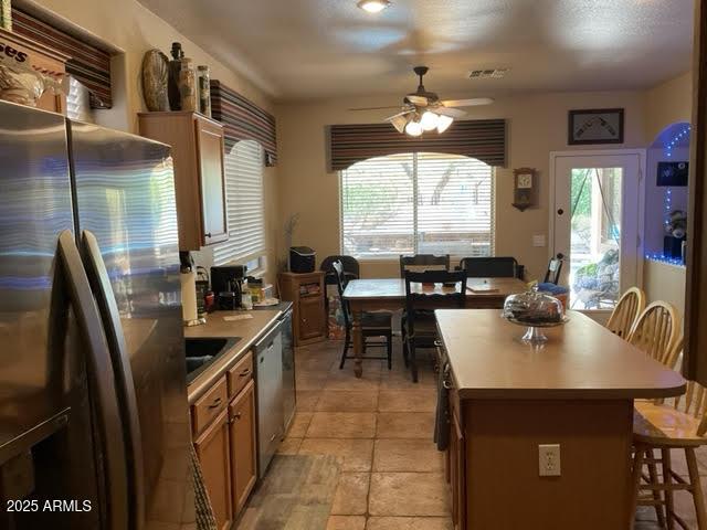 kitchen featuring a breakfast bar, stainless steel appliances, ceiling fan, sink, and a kitchen island