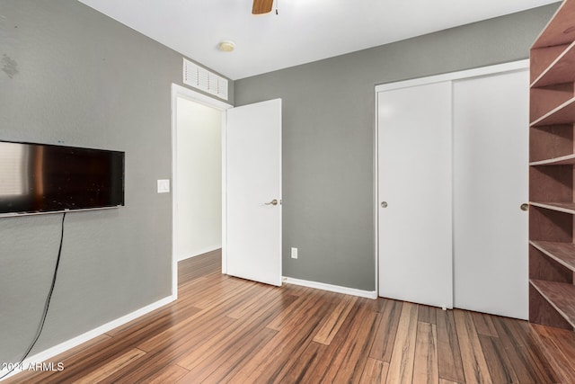 unfurnished bedroom with hardwood / wood-style flooring, ceiling fan, and a closet