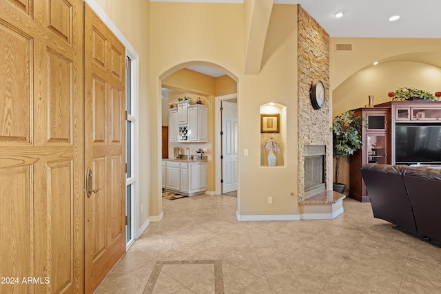 interior space featuring sink, a fireplace, and a high ceiling