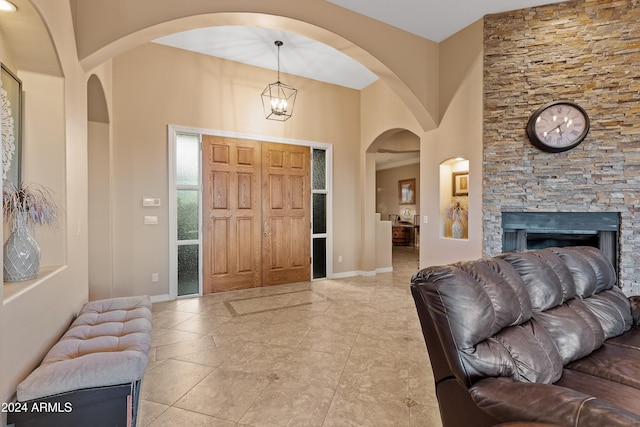 entryway featuring a fireplace, a high ceiling, and an inviting chandelier